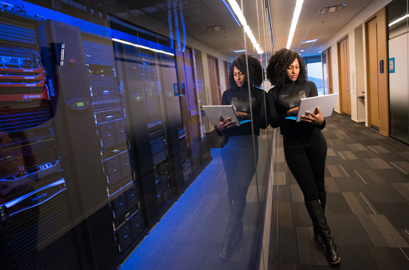 An engineer checking a laptop beside server racks in a data centre